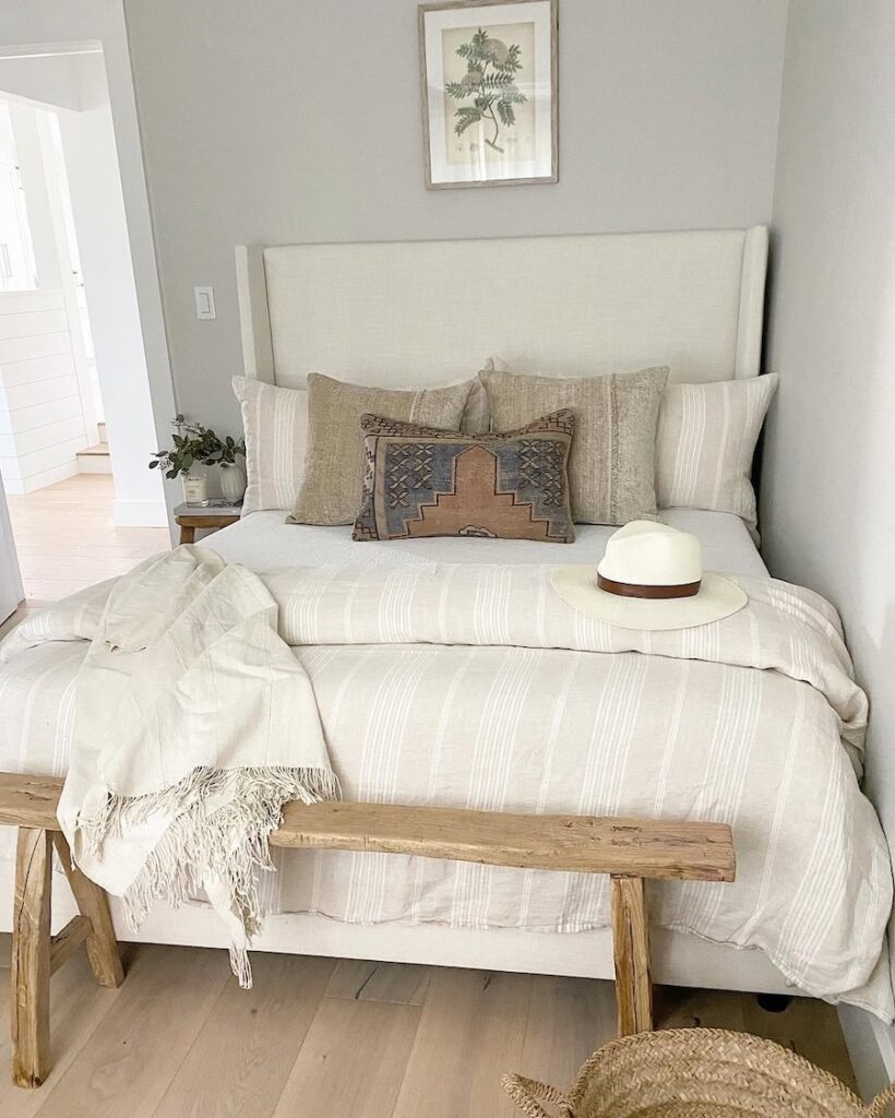 Sherwin-Williams Repose Gray bedroom walls with neutral bedding, cream upholstered bed, light wood flooring, warm beige accents, and soft natural tones