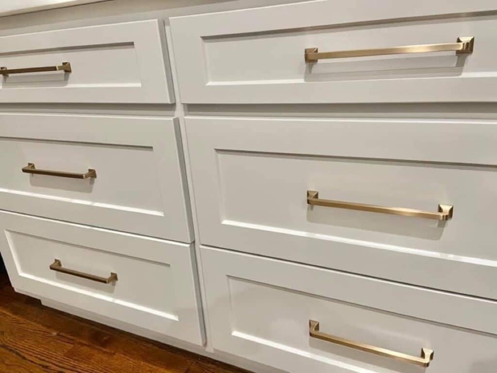 Close-up of Sherwin-Williams Repose Gray cabinets with warm brass hardware and dark wood flooring