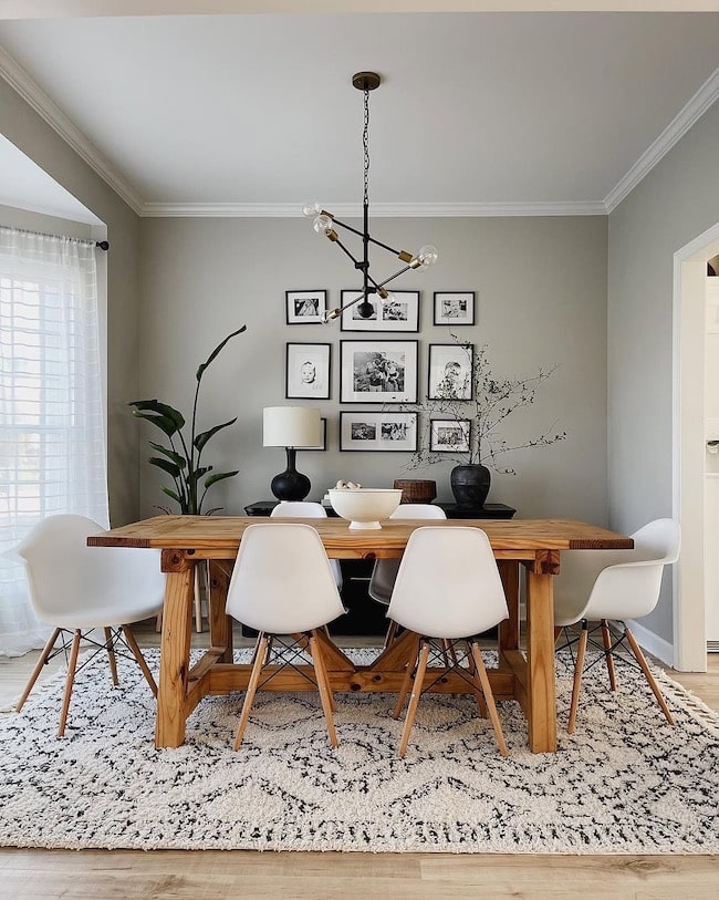 Sherwin-Williams Repose Gray dining room walls with warm wood dining table, white chairs, black chandelier, gallery wall, and neutral rug