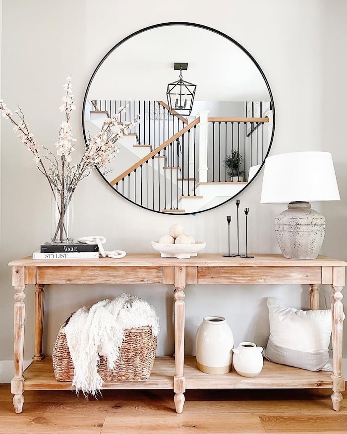 Sherwin-Williams Repose Gray entryway wall color with round black mirror, light wood console table, white lamp, neutral decor, and light wood flooring