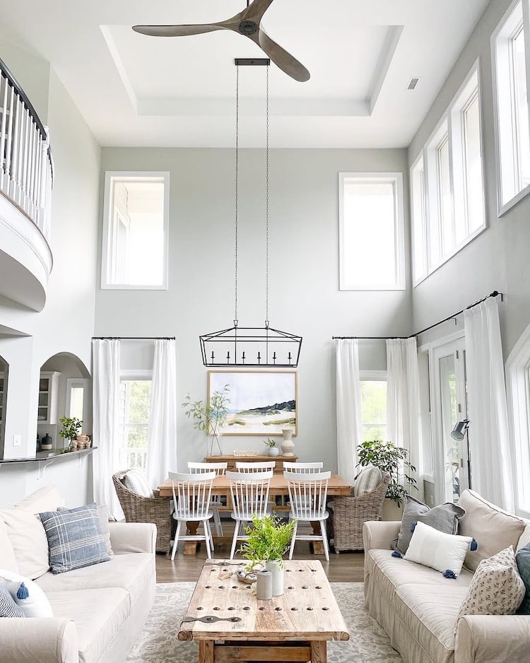 Sherwin-Williams Repose Gray great room with tall ceilings, white trim, large windows, neutral furniture, warm wood accents, and dining area
