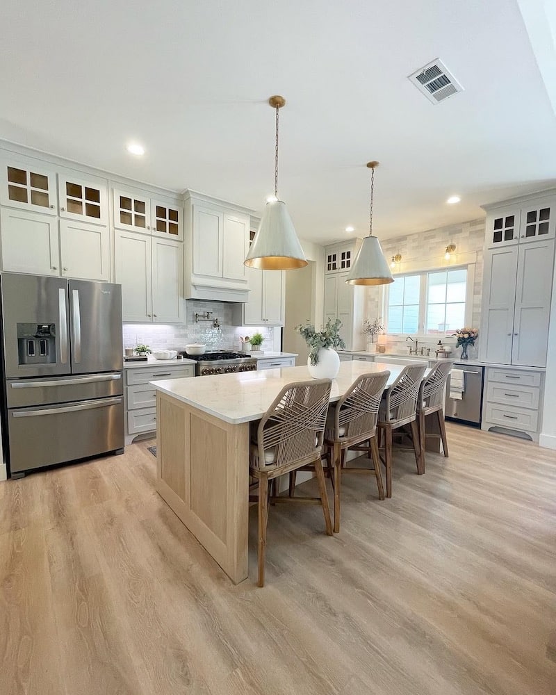 Sherwin-Williams Repose Gray kitchen cabinets with large island, warm wood flooring, white countertops, pendant lights, and neutral decor