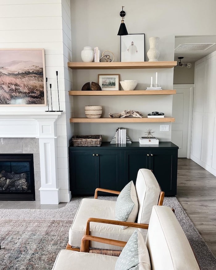 Sherwin-Williams Repose Gray living room walls with black built-ins, light wood floating shelves, white trim, neutral furniture, and fireplace