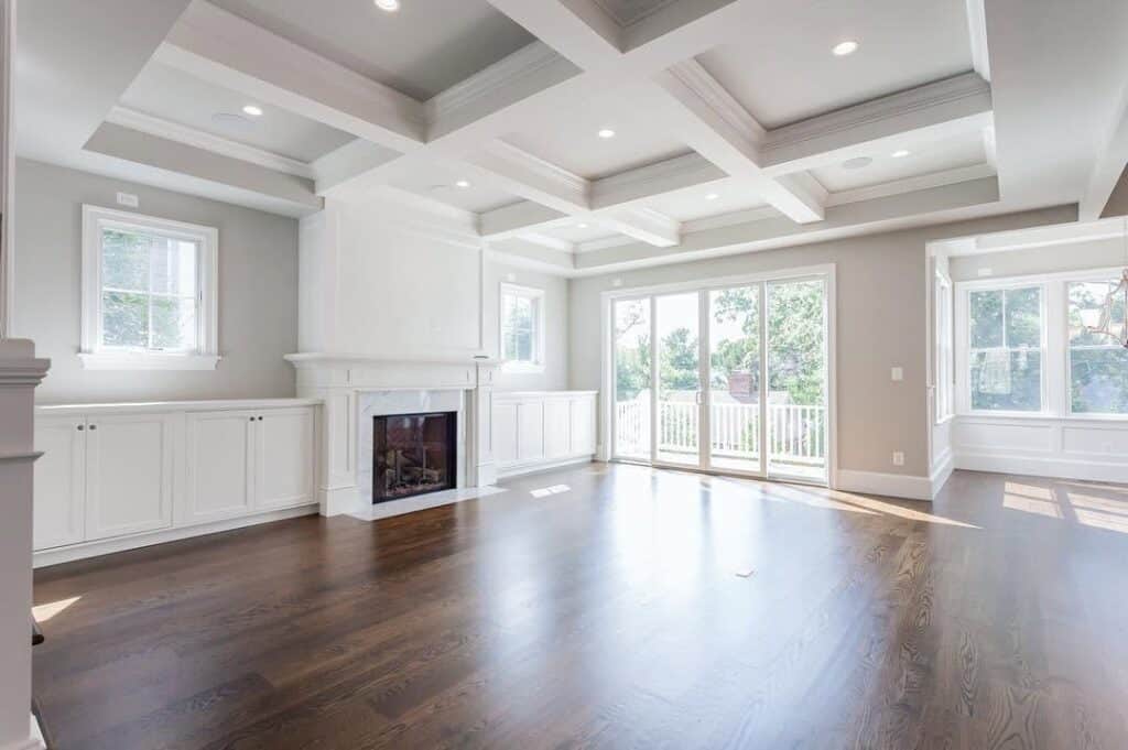 Sherwin-Williams Repose Gray living room walls with white trim, coffered ceiling, dark wood floors, and white fireplace surround