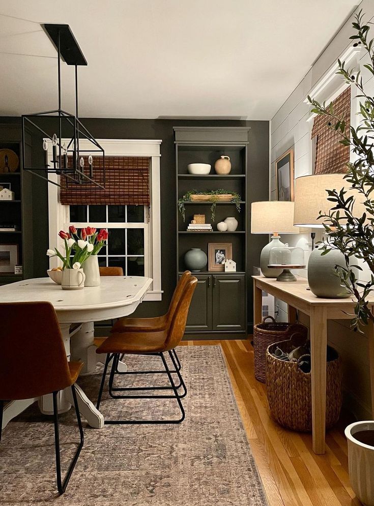 Sherwin Williams Urbane Bronze Built In Bookshelf and Dining Room Paint Color Idea. bookcase storage and display in a living room with a white dining table, console table with table lamps instead of a buffet sideboard