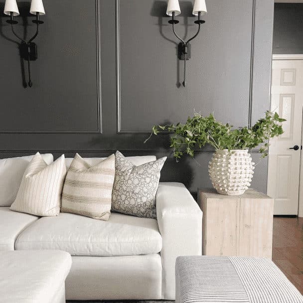 Sherwin Williams Urbane Bronze Living Room Paint Color Inspiration. dark brown walls with molding, wall sconce lights, white sofa, organic modern decor, Anthropologie vase with tree stems, neutral color scheme, wood side table, modern, farmhouse, traditional, transitional design inspiration