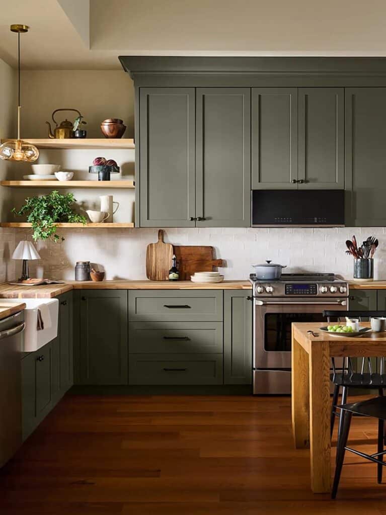 Behr Grounded Kitchen Cabinet Paint Color Idea - this is behr's color of the year 2027, earthy, moody, neutral green kitchen color inspiration, organic modern, transitional design style, floating shelves white backsplash and warm white walls