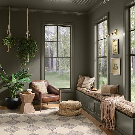 Behr Grounded Living Room Wall Color Inspiration, a cozy, earthy neutral green paint color for a great room, living room or family room. Green living room with green trim, brown leather chair, light wood floors and window seat, neutral color palette, traditional design style, Behr color of the year 2027 design trends