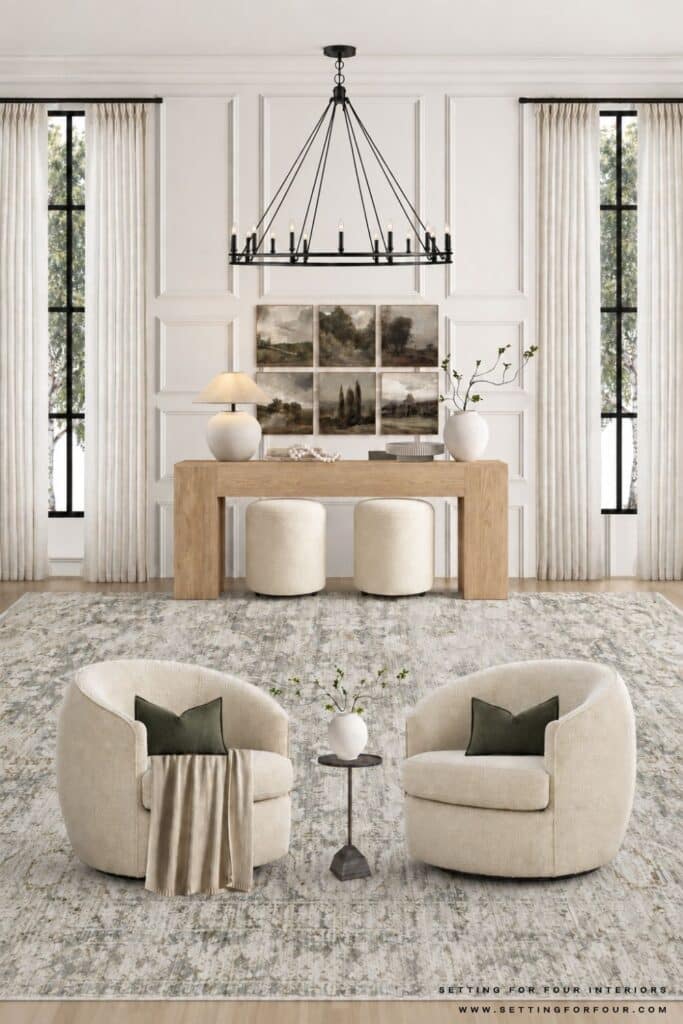 Living room console table styled with a six-piece landscape gallery wall, cream lamp, books, decorative objects, greenery and two cream ottomans.