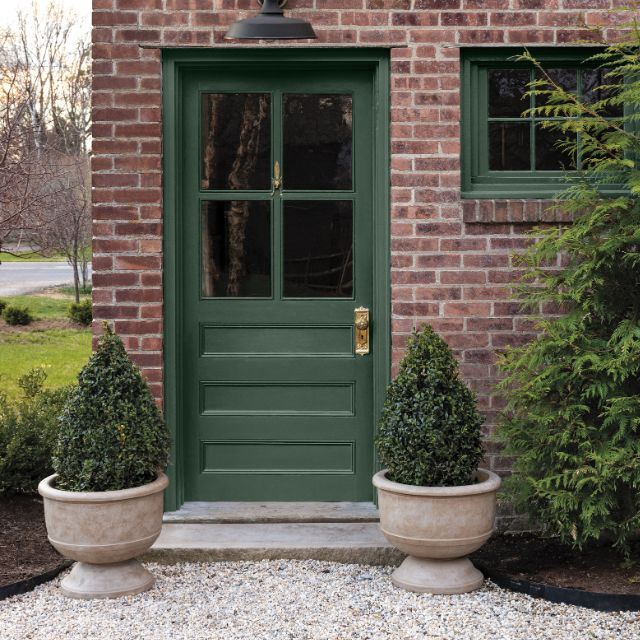 Benjamin Moore Webster Green front door paint color and window trim paint color with red brick exterior on a traditional home with topiary planters and landscaped front yard.